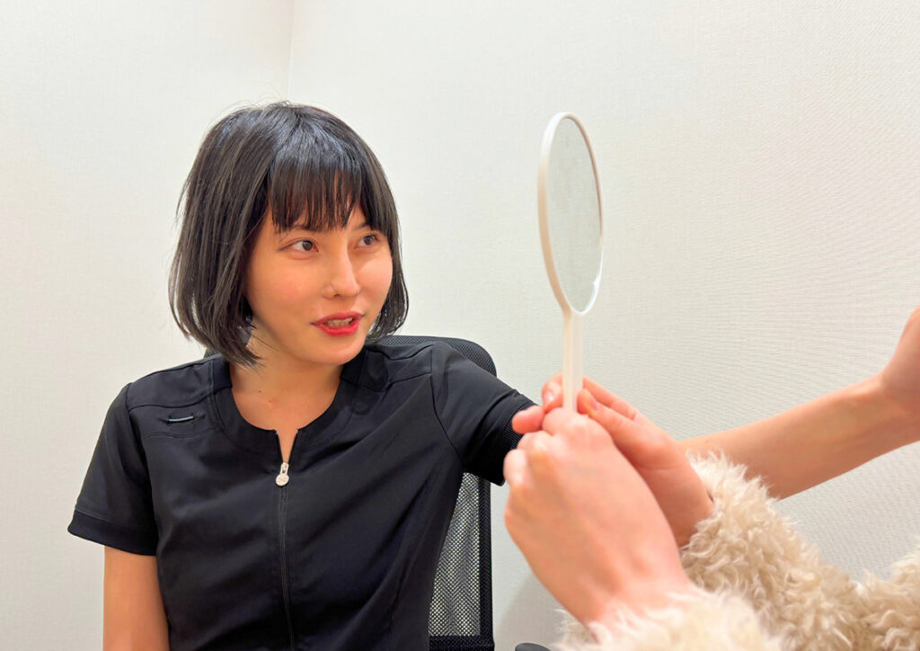 患者にカウンセリングを行い、手鏡を使って肌の状態を確認している様子